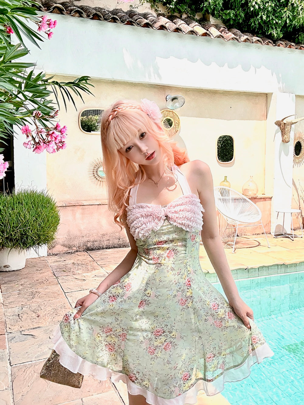 Woman in a floral dress standing by a pool with decorative elements.