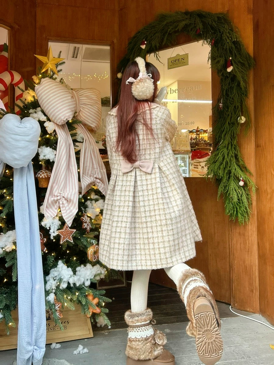 Girl wearing a checkered coat and white gloves in front of a decorated Christmas tree.