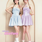 Two young women wearing glittery pastel-colored minin dresses standing in front of a beige archway.