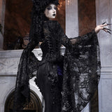 Person in a dark, ornate costume standing in an elegant gothic lace and vintage palace design.