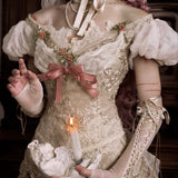 girl in an vintage floral bridal dress holding a candle, with a dark background. Gothic fashion for halloween wear.