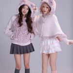 Two women wearing matching cat-themed outfits with  cat ears on hoodies in fluffy faux fur fabric and mini skirts 