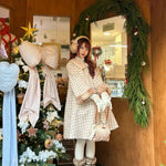 Woman in a plaid fawn deer dress standing in a decorated room with Christmas decorations.
