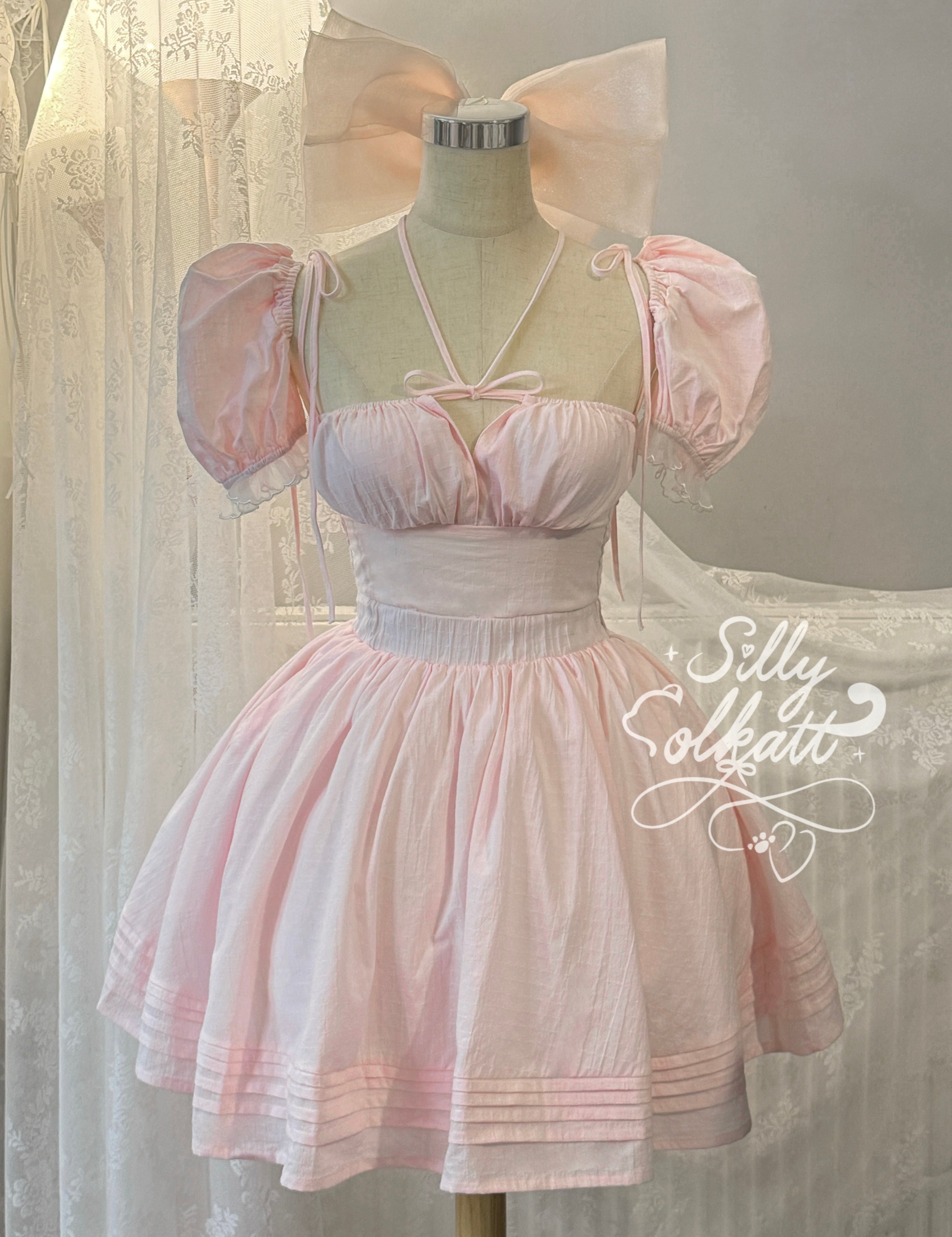 Pastel pink dress on a mannequin with a large bow against a soft background